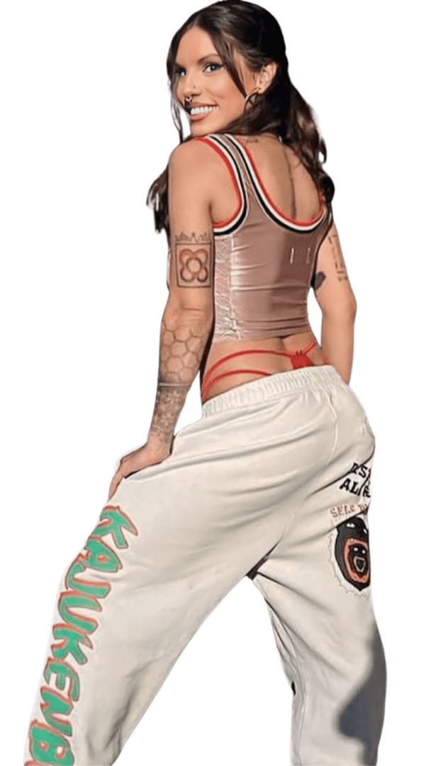 A woman with tattoos is standing in front of a green background.